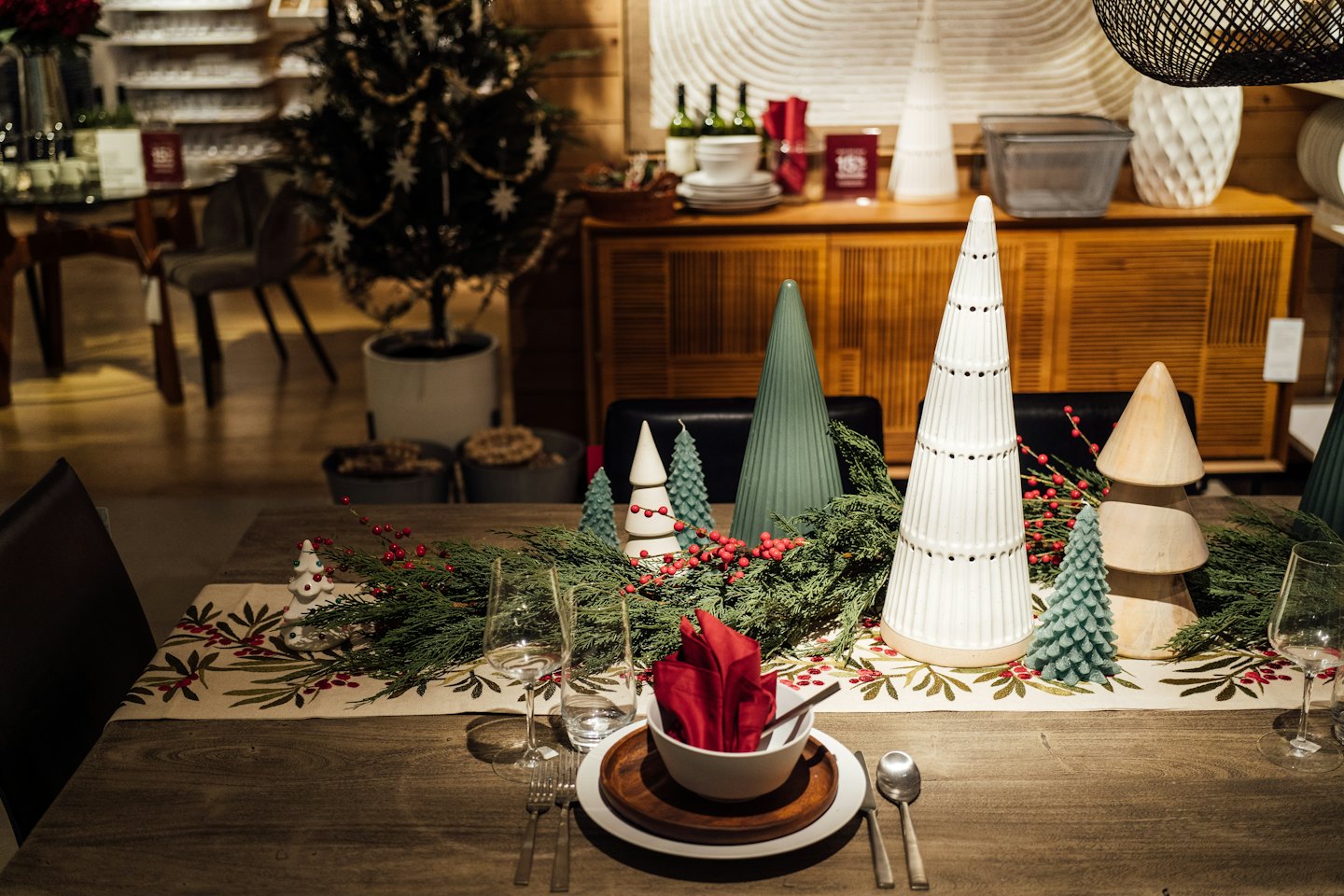 Festive Christmas table setting with evergreen branches and candles.
