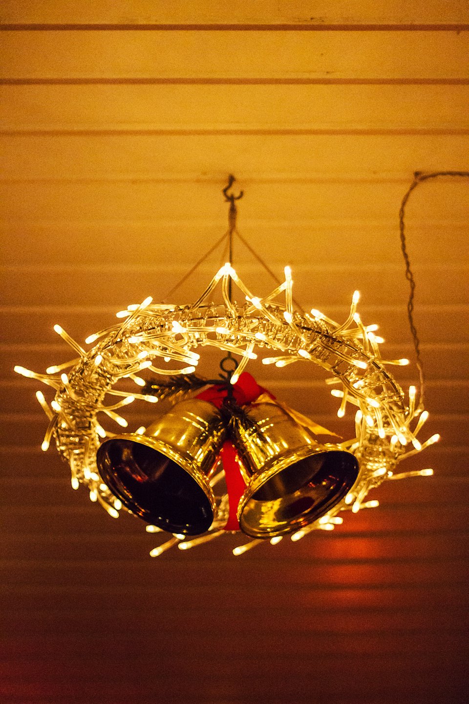 Glowing wreath with golden bells hanging from a ceiling.