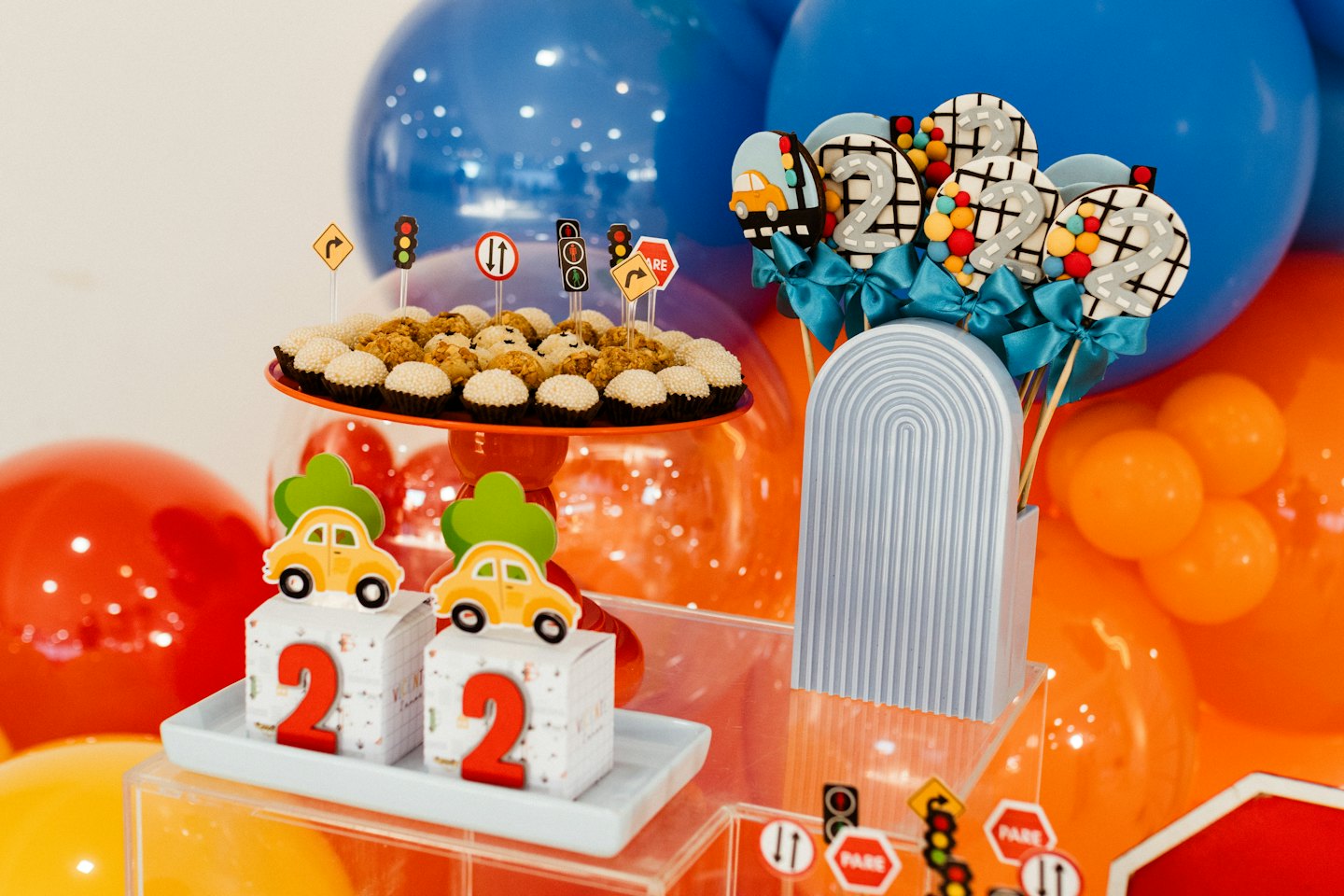 Car themed birthday dessert table with cookies and balloons.