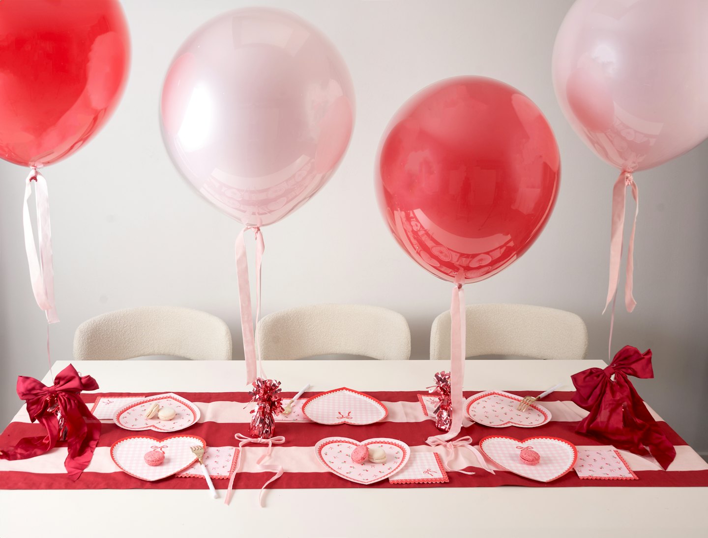 Red and pink balloons float above a heart-themed dinner table.