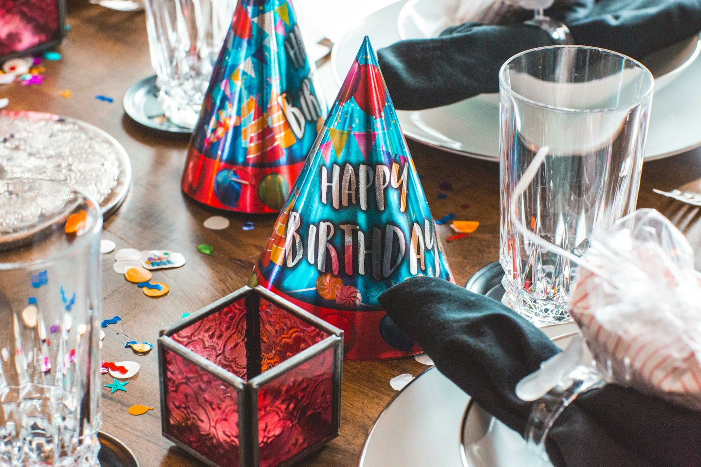 Birthday hats and confetti on a table setting.