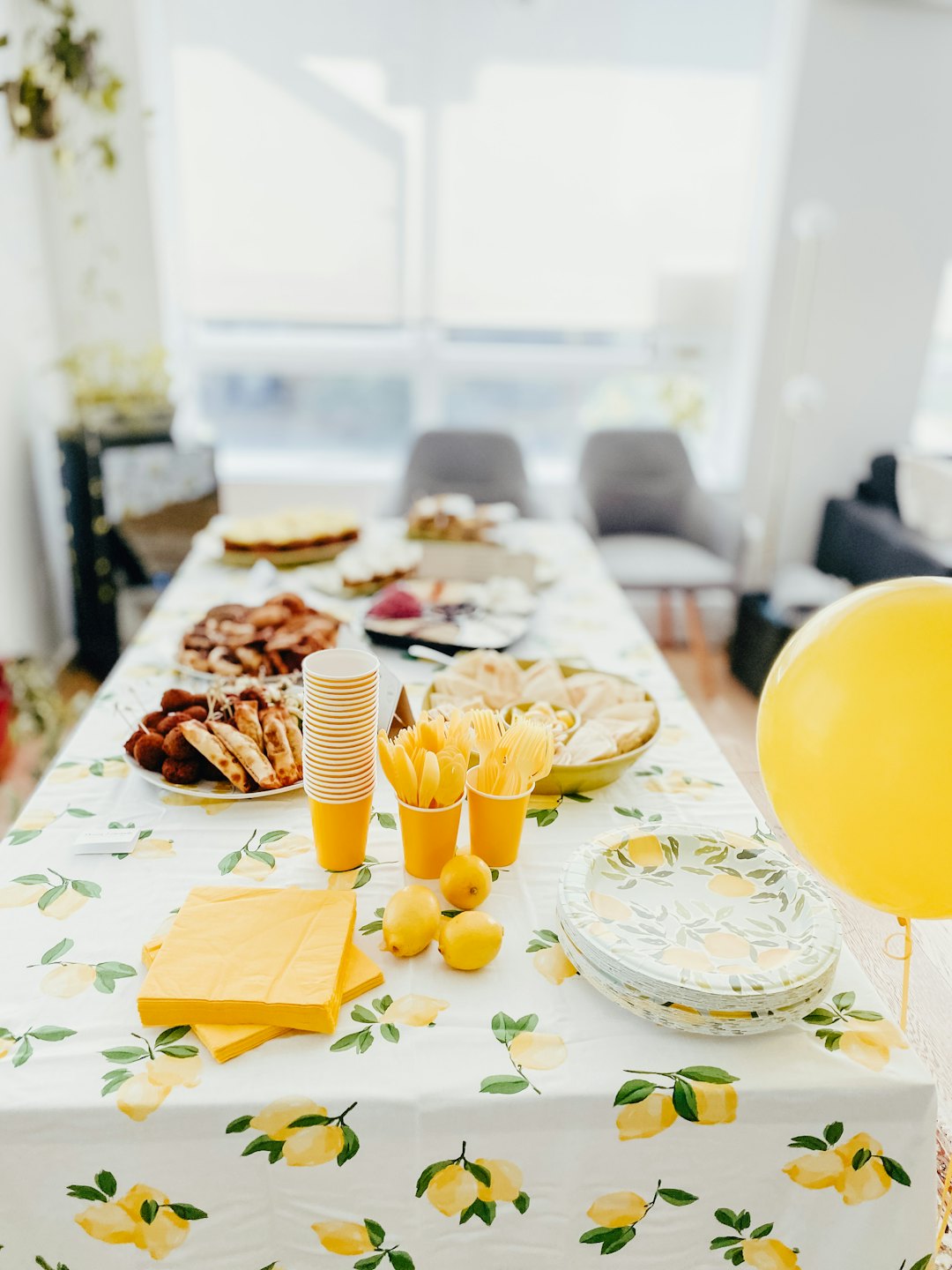 Table set with lemon patterned plates and appetizers for a party.